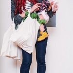Image of a woman holding a baby and a bag of groceries.