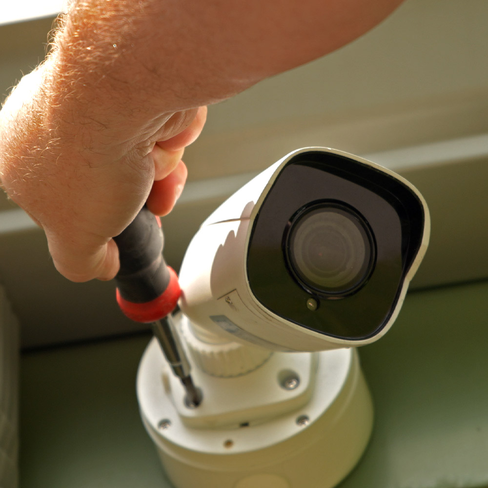Installer hand using tool to install an outdoor security camera for a small business