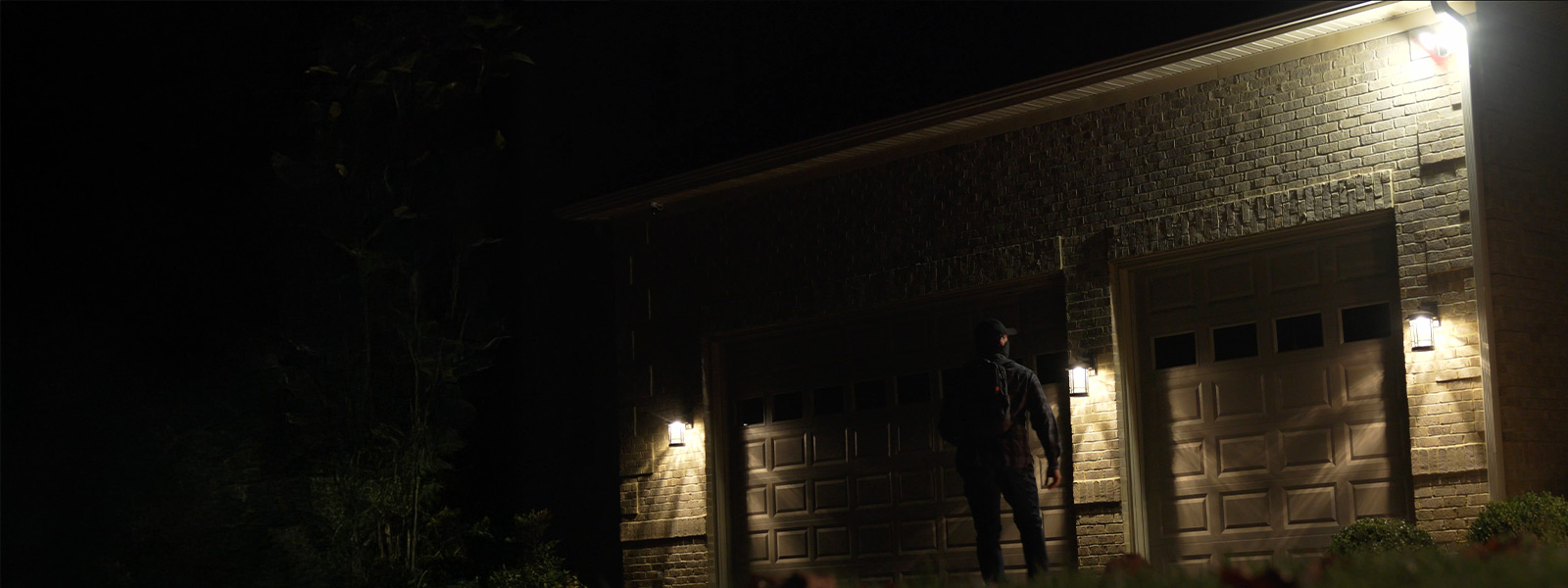 Intruder standing outside of a home's garage at night.