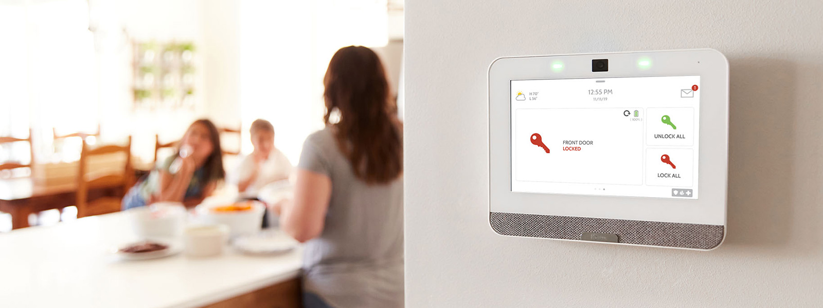 Guardian home security panel on wall with family in the background