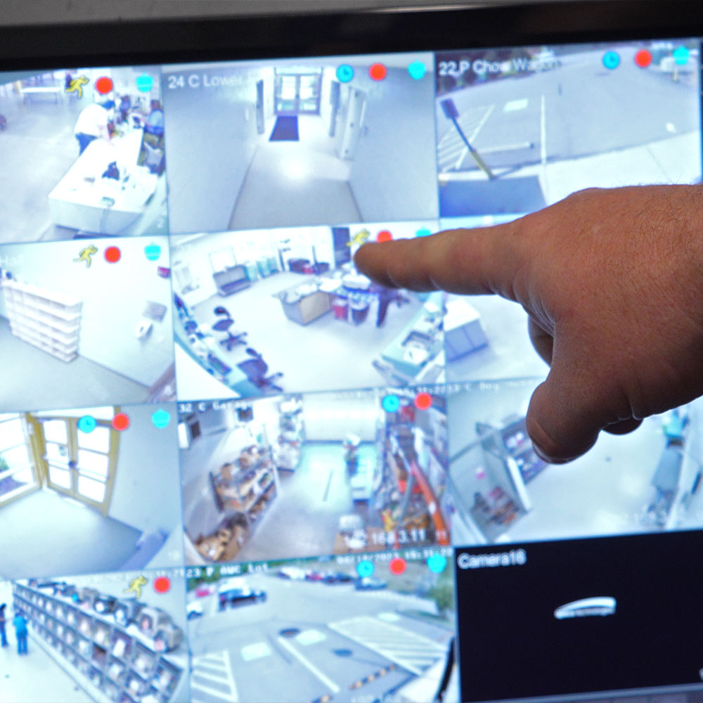 A hand pointing at a computer screen with multiple views from cameras
