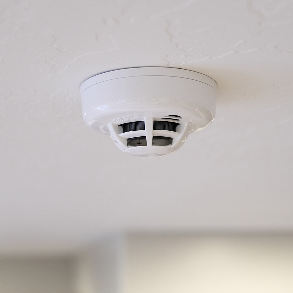A Guardian Protection smoke and heat detector mounted on a ceiling