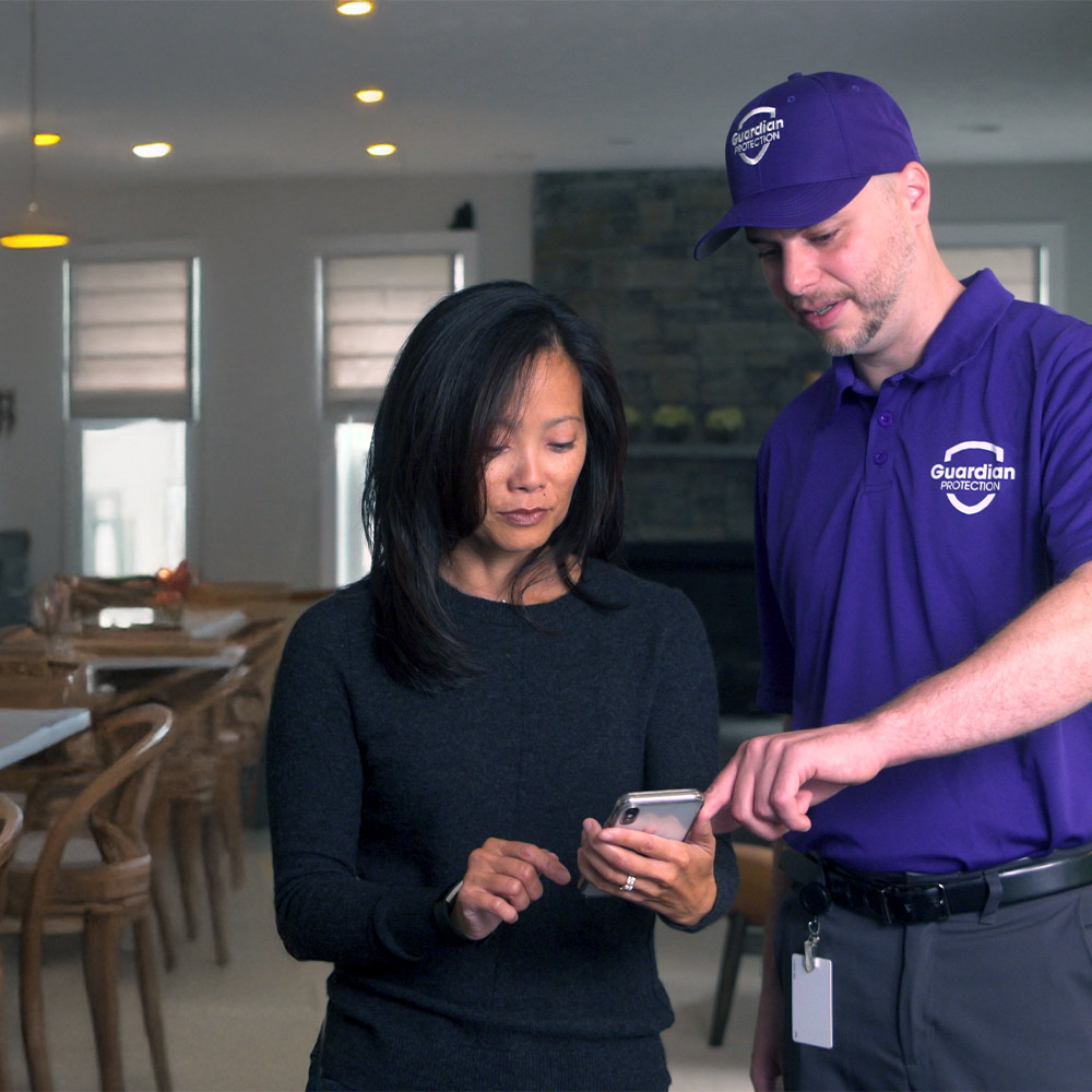 A Guardian Protection tech showing a customer the Guardian app on their smart phone