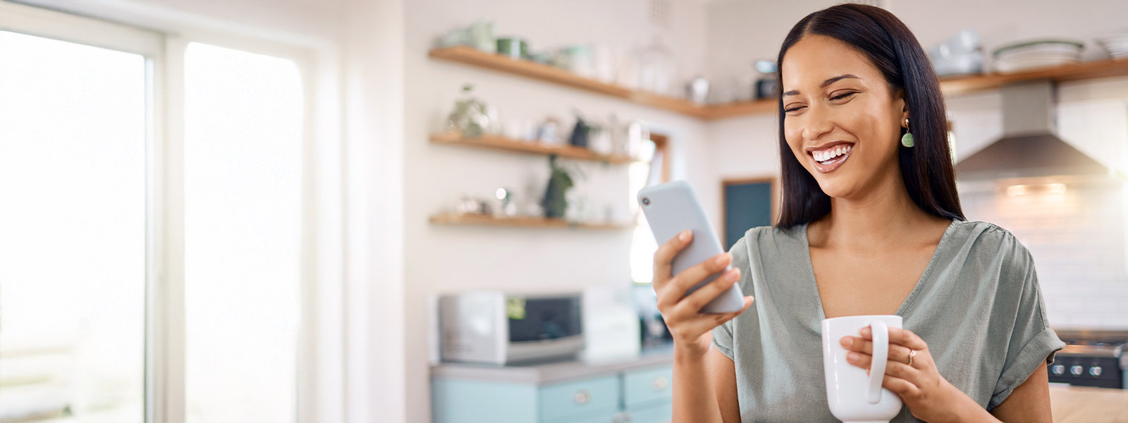 A woman holding her smartphone and a coffee mug