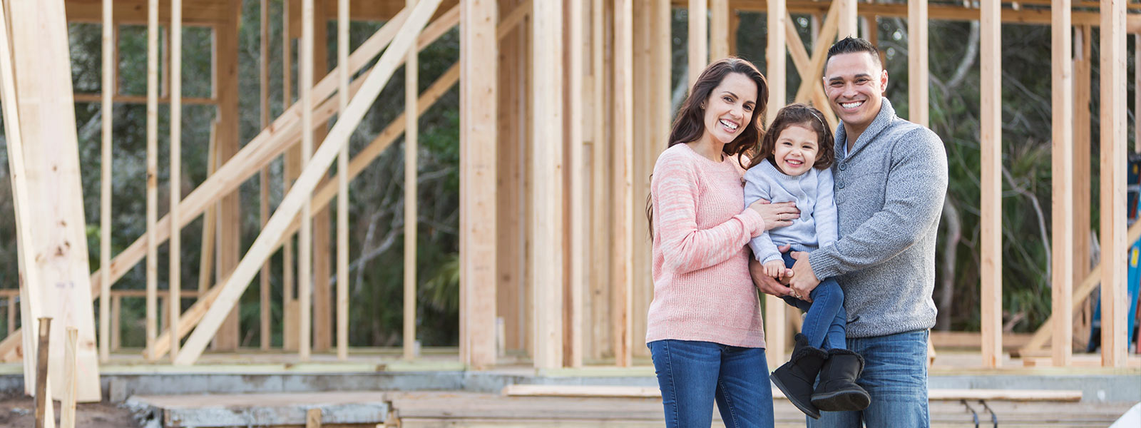 Family standing in front of new home being built