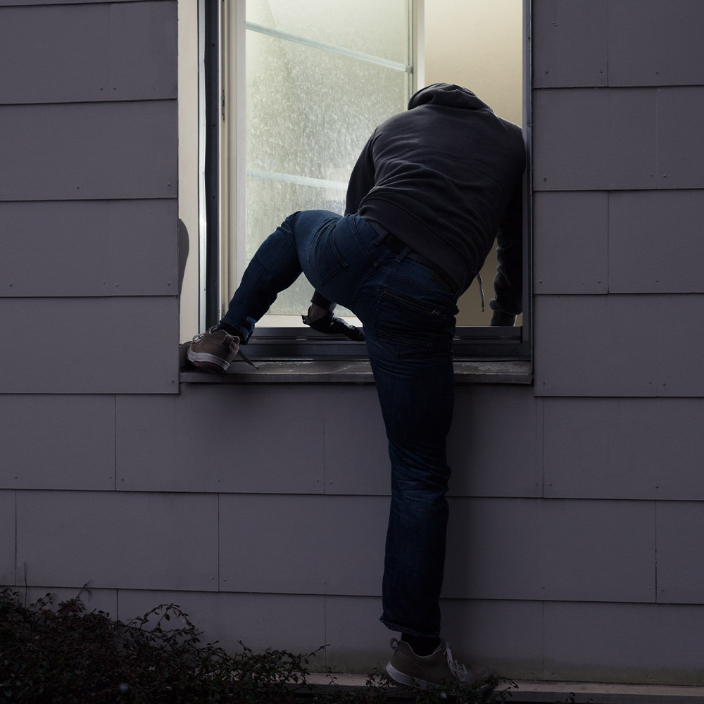 Burglar breaking into a home's via window