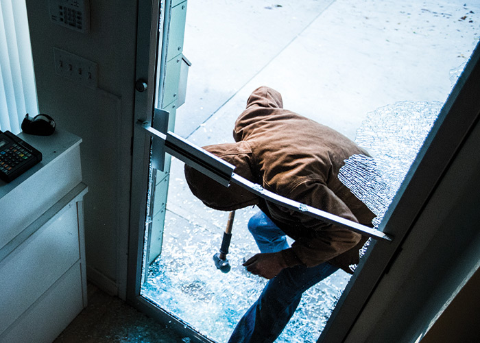 Burglar breaking glass door of business